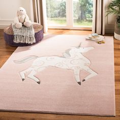 a pink rug with a white horse on it and a teddy bear sitting on the floor