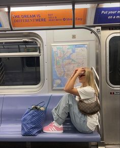 a woman sitting on a subway bench with her hand in her hair and looking out the window