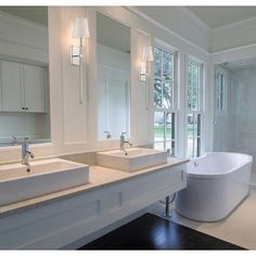 a large bathroom with two sinks and a bathtub in the middle of the room