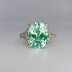 "While Supplies Last! This ring is an oval lab created right green paraiba with round moissanite accents, 14k white gold #6401 -Approximate total carat weight:  6.05ctw diamond equivalent  -Center Stone Size:  12x10mm - approx. 5.80ct diamond equivalent  -Center Stone Shape: oval  -Gem Type:  Lab Created Tourmaline Paraiba Corundum  -Treatment: Nanocrystal -Stone Clarity: VS2 -Stone Color: Light Green/Mint Green -Moh's Scale: 7 Hardness -Side Stones: round  - approx. 0.25ct diamond equivalent -G Esty Finds, Oval Engagement Ring, Green Garnet, Oval Engagement, Green Mint, August Birthstone, Ring Light, Engagement Rings Oval, Round Moissanite