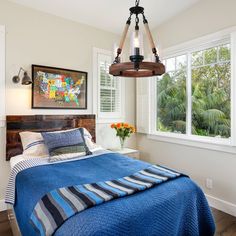 a bedroom with a blue blanket on the bed and a wooden chandelier hanging from the ceiling