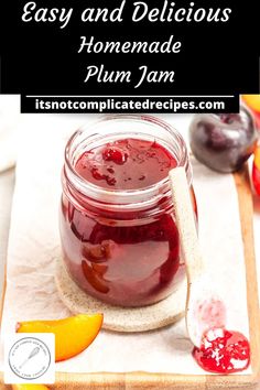 homemade plum jam in a glass jar on a cutting board next to an orange slice