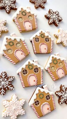 gingerbread houses and snowflakes are arranged on a white surface with one cookie in the middle