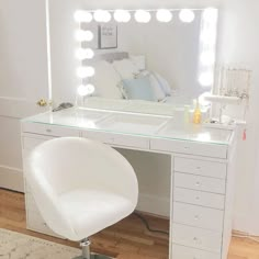 a white vanity with lights on and a chair