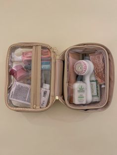 an open travel bag filled with cosmetics and personal care items on top of a table