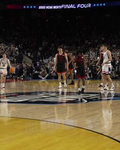 the men are playing basketball on the court in front of an arena full of people