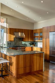 a large kitchen with wooden cabinets and stainless steel appliances, along with hardwood flooring