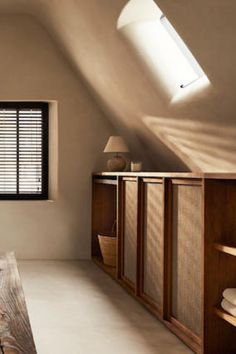 an attic bedroom with white walls and wooden furniture, along with large windows that have shutters on them