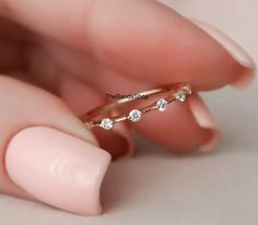 a woman's hand holding a gold ring with three small white diamonds on it