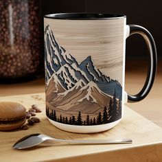 a coffee mug sitting on top of a wooden table next to a spoon and cup