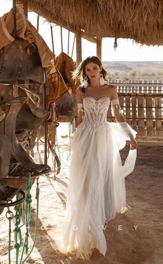 a woman in a white dress is walking by some saddles