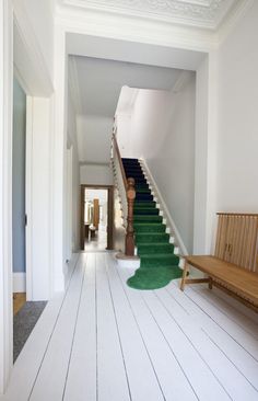 a green rug on the floor next to a stair case in a white room with blue stairs