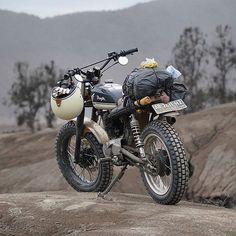 a motorcycle parked on the side of a mountain with bags strapped to it's back