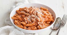 a white bowl filled with pasta covered in sauce and parmesan cheese