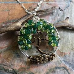 We handmade this unique & gorgeous wire wrapped Tree of Life pendant necklace. The pendant is made with Peridot & dark green Jade gemstones using .925 sterling silver wires for the outer ring, vintage bronze wires for the tree trunk & branches. The pendant measures between 1.60 to 1.70 inch in diameter. It comes with your choice of chain. Each pendant is handmade, so please allow slight variations from the shape of the branches and placement of the stones as shown. The Tree of Life i Green Crystal Stone Necklaces For Gift, Green Crystal Necklaces With Stones As Gift, Wire Wrapped Necklaces As May Birthstone Gift, Adjustable Hand Wrapped Green Necklace, Adjustable Green Hand-wrapped Necklace, Wire Wrapped Pendant Necklaces For May Birthstone, Wire Wrapped Round Pendant Necklace For Crafting, Nature-inspired Wire Wrapped Crystal Pendant Necklaces, Green Pendant Crystal Necklace, Nickel Free