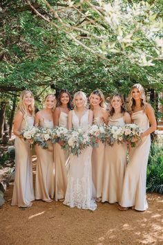 a group of women standing next to each other holding bouquets in their hands and smiling at the camera