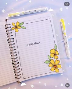 an open notebook with yellow flowers on it and a pen sitting next to the page