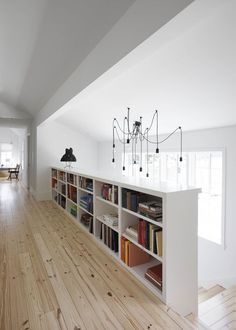 a book shelf with many books on it in the middle of a wooden floored room