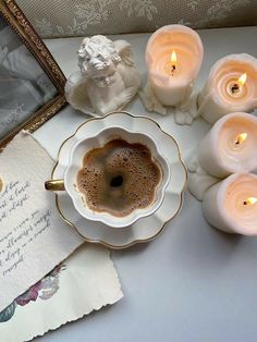 there is a cup of coffee and some candles on the table