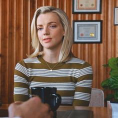 a woman sitting at a table with a camera in her hand and another person standing behind her