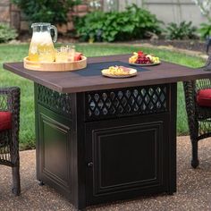 an outdoor dining table with two chairs and a tray of fruit on it, in the middle of a yard