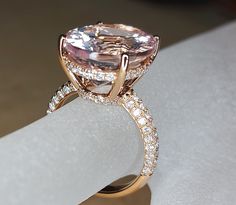 an engagement ring with a large pink diamond surrounded by small white diamonds and gold bands