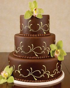 a three layer chocolate cake with green orchids on top