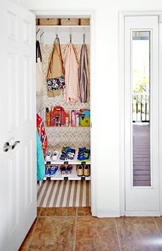 an open closet with shoes and handbags hanging on the wall next to two doors