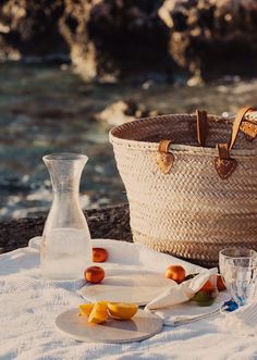 a picnic setting on the beach with an empty bottle, glass and cheese plate next to it