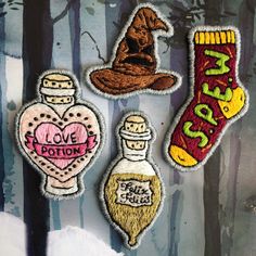 three patches with different designs on them in the shape of heart, bottle and wizard hat