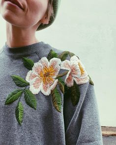 a person wearing a sweater with flowers on it