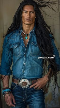 a man with long black hair wearing a blue shirt and cowboy belt is standing in front of a building