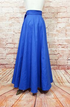 a mannequin wearing a blue skirt on a wooden floor in front of a brick wall