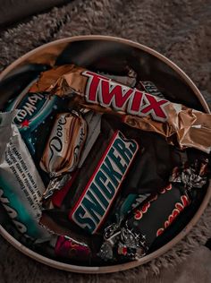 a bowl filled with assorted candy bars and snacks on top of a gray blanket