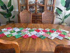 a wooden table topped with lots of green and red quilted place mats on top of it