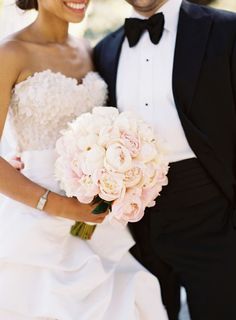 the bride and groom are wearing black tuxedos with white flowers in their bouquets