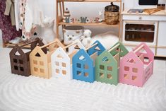 small wooden houses sitting on top of a white rug in front of a doll house