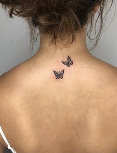 the back of a woman's neck with two small butterflies on her left side