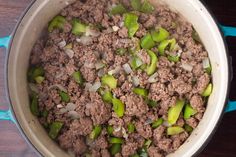 a pot filled with meat and peppers on top of a wooden table