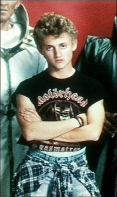 a young man with his arms crossed standing in front of a mirror and looking at the camera