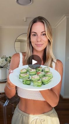 a woman holding a plate with cucumbers on it