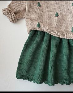 a knitted sweater and green skirt on a white surface