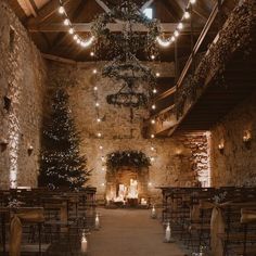 an indoor wedding venue set up with chairs and lights hanging from the ceiling, surrounded by stone walls