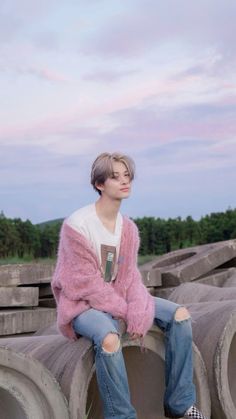 a young man sitting on top of cement pipes