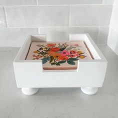 a wooden box with flowers painted on the lid and handles sitting on a marble countertop