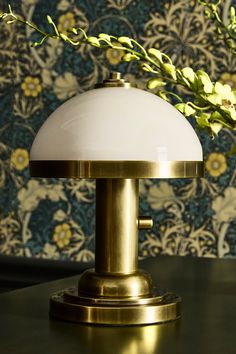 a table lamp sitting on top of a wooden table next to a vase with flowers