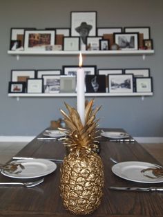 a pineapple sits on a table with plates and silverware