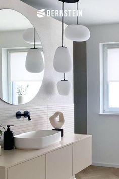 a modern bathroom with white fixtures and round mirrors