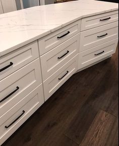 a white kitchen counter with black handles and drawers