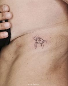 a small turtle tattoo on the side of a man's chest, which is under his right arm